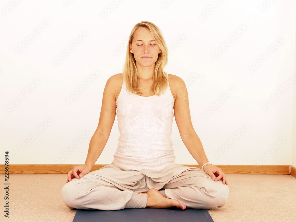 Young attractive woman in meditation pose with closed eyes, practicing yoga, white background