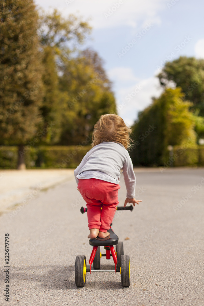 Acrobatic child balance on tricycle. Kind zeigt Kunststück auf Fahrrad. Acrobatic child balance on tricycle. Kind zeigt Kunststück auf Fahrrad.