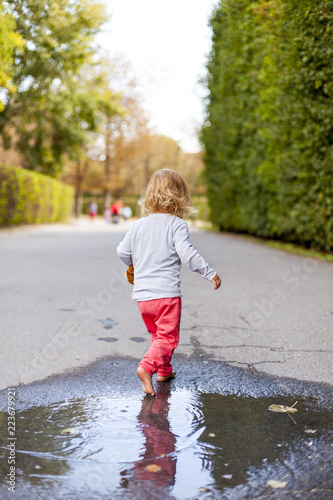Kleines Kind geht durch Wasserpfütze. Happy child walking trough water.