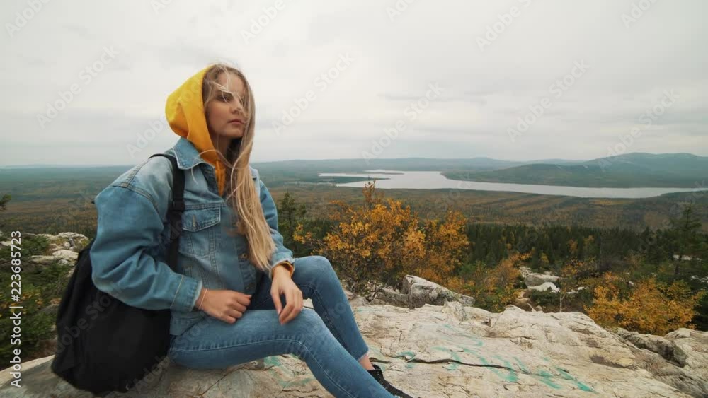 A young woman sitting on the top of the mountain looking at beautiful landscape thinking about life. A girl going on holiday. A young woman sitting on the top of the mountain looking at beautiful landscape thinking about life. A girl going on holiday.