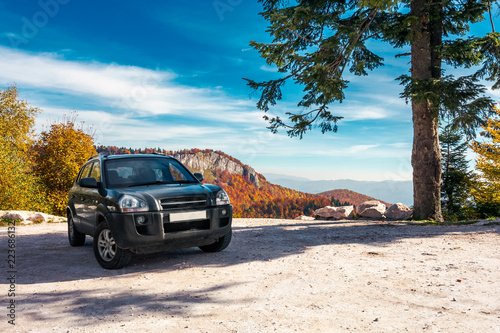 SUV on the parking lot in mountains. beautiful mountainous scenery with huge rocky formation in the distance. wonderful deep autumn landscape. travel europe by car concept photo