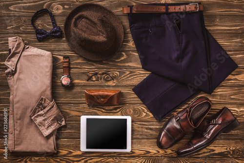 flat lay with masculine clothing, accessories and digital tablet arranged on wooden surface