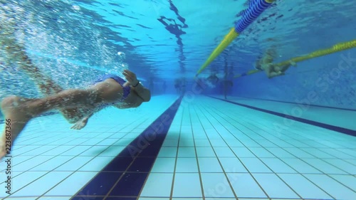 The teenager swims in the pool under the water.