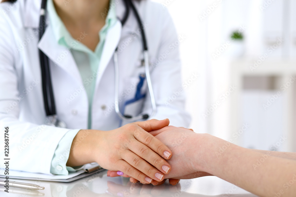 Hand of a doctor woman reassuring to female patient, close-up. Medical ethics and trust concept Hand of a doctor woman reassuring to female patient, close-up. Medical ethics and trust concept
