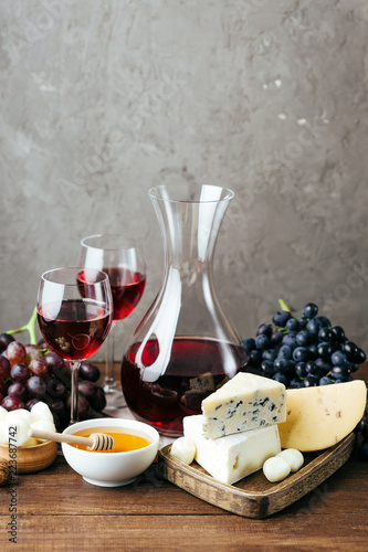 Cheese, wine and honey, wooden board, gray background, snack, alcohol, dairy products