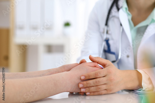 Hand of a doctor woman reassuring to female patient  close-up. Medical ethics and trust concept