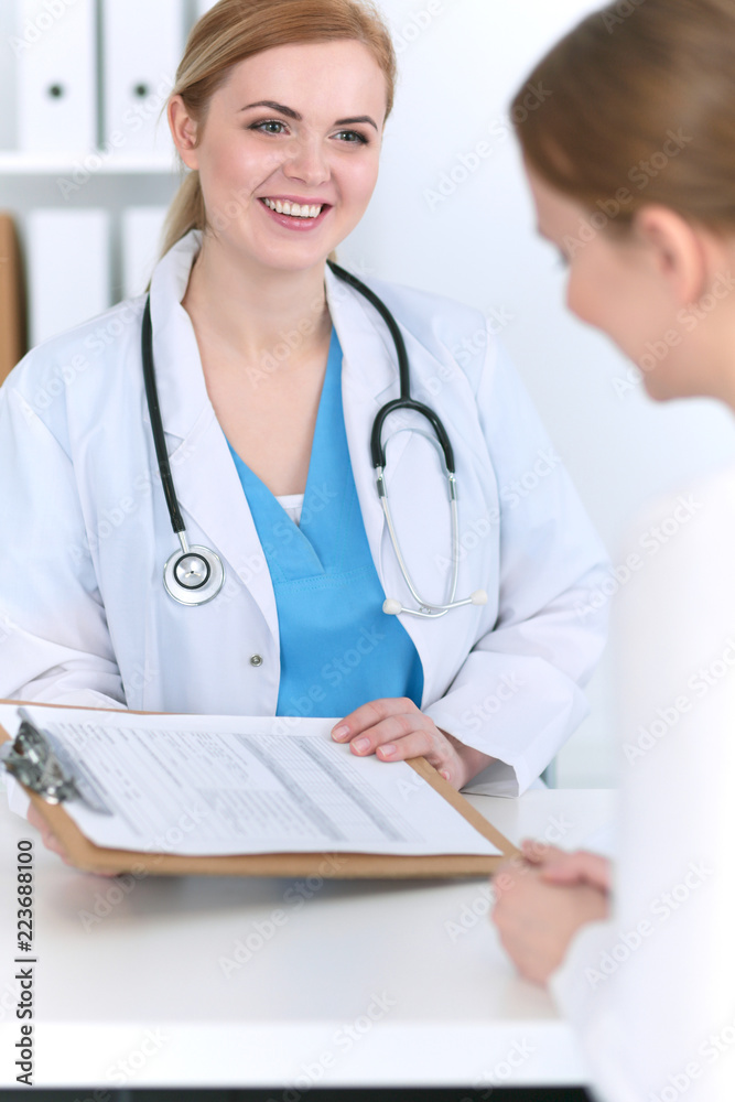 Doctor and patient are discussing something while sitting at the desk in hospital office, focus on cheerful smiling physician. Good news in medicine, health care concept Doctor and patient are discussing something while sitting at the desk in hospital office, focus on cheerful smiling physician. Good news in medicine, health care concept