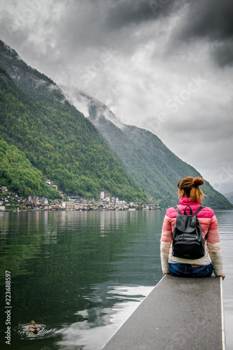 girl is sitting on wooden bridge. tourist woman sits on the bridge and enjoy the relaxation and freedom. Beautiful view of the mountain nature. wonderful view of Hallstatt. 