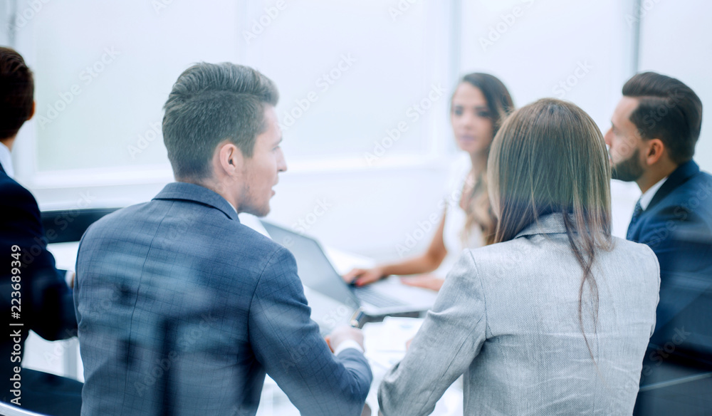 rear view .the business team is discussing something sitting at the Desk rear view .the business team is discussing something sitting at the Desk