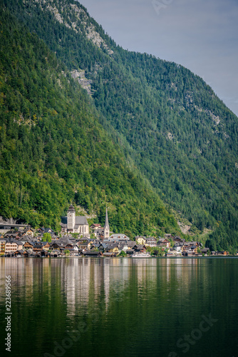 Travel to the Alps. City Hallstatt. City among the mountains in the Alps. Hallstatt is beautiful small town in Austria. town is reflected in the water on a sunny day 