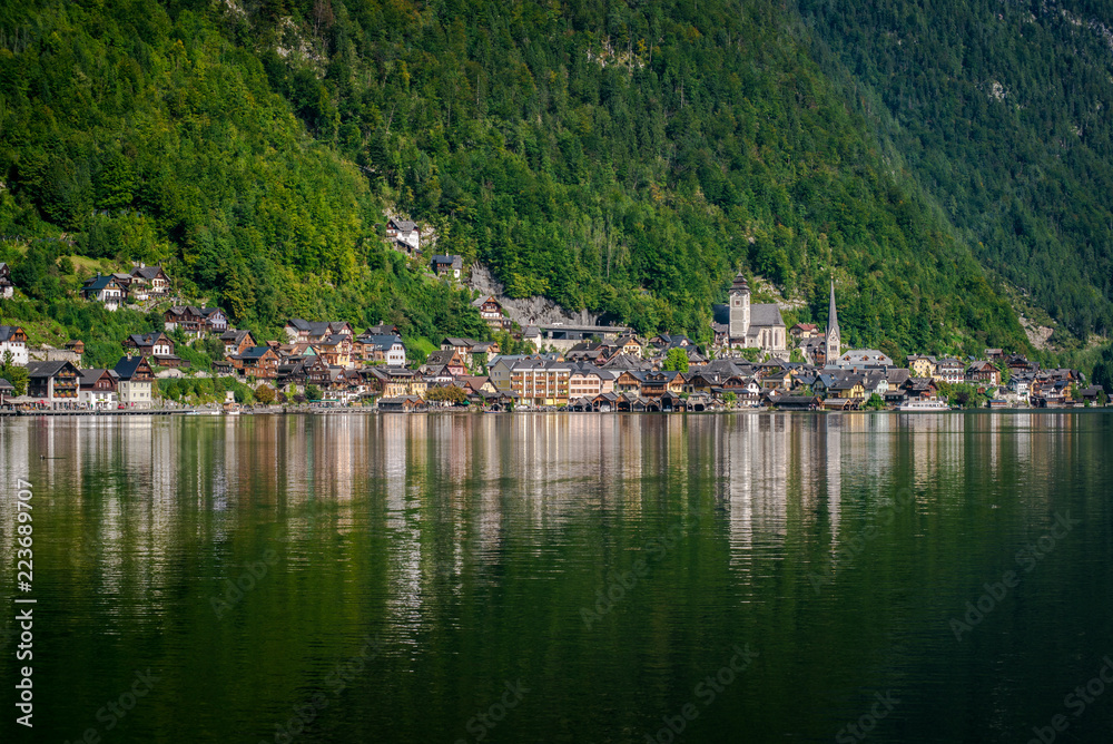 Travel to the Alps. City Hallstatt. City among the mountains in the Alps. Hallstatt is beautiful small town in Austria. town is reflected in the water on a sunny day
