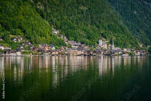 Travel to the Alps. City Hallstatt. City among the mountains in the Alps. Hallstatt is beautiful small town in Austria. town is reflected in the water on a sunny day 