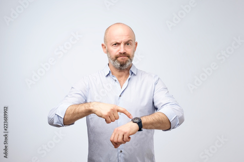 Mature european businessman impatiently pointing to his watch. Why are you late concept.