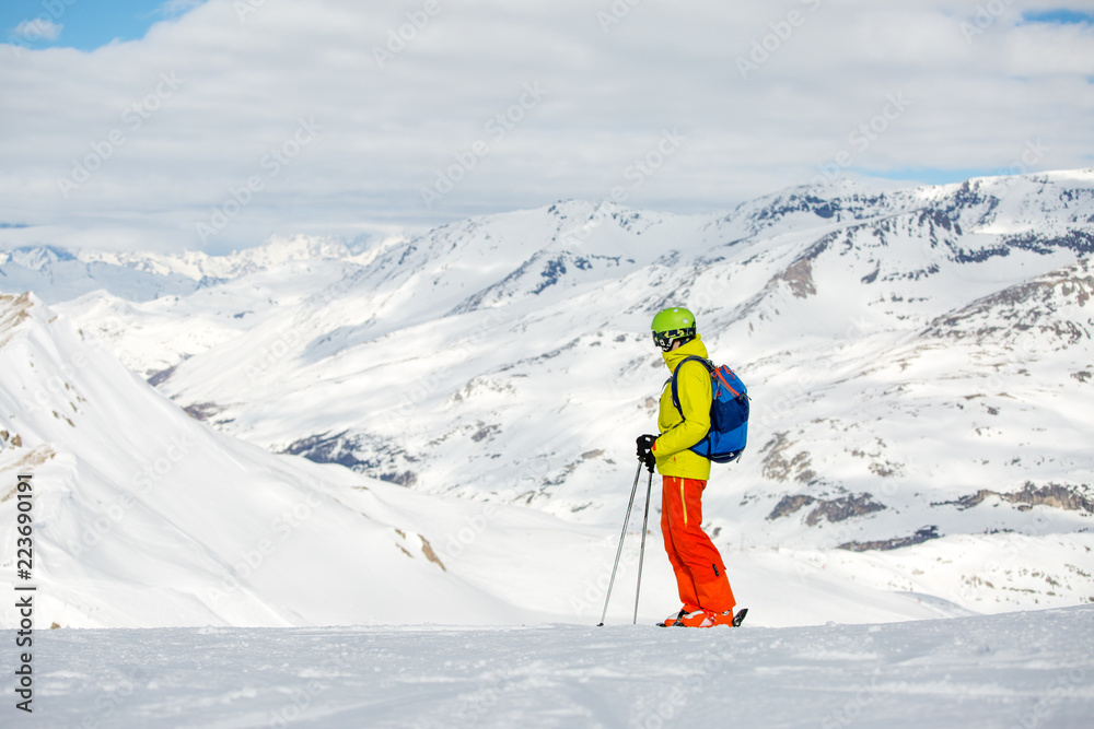 Photo of sportive man skiing against background of snowy mountains
