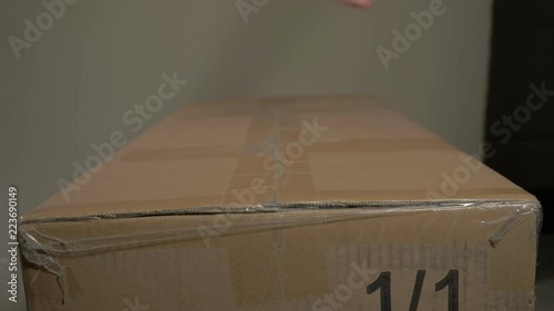 A young man hands opens a cardboard box parcel at home.