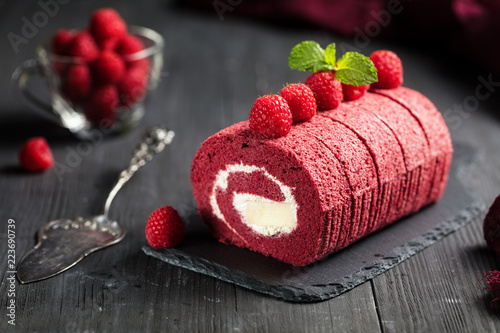 Billede på lærred Red velvet Sponge Swiss roll with fresh raspberry on dark background