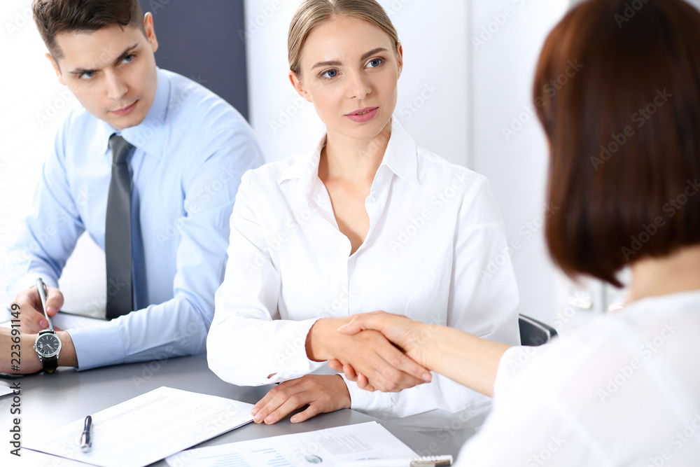 Business handshake by blonde woman and her partner at meeting. Concept of success and agreement Business handshake by blonde woman and her partner at meeting. Concept of success and agreement