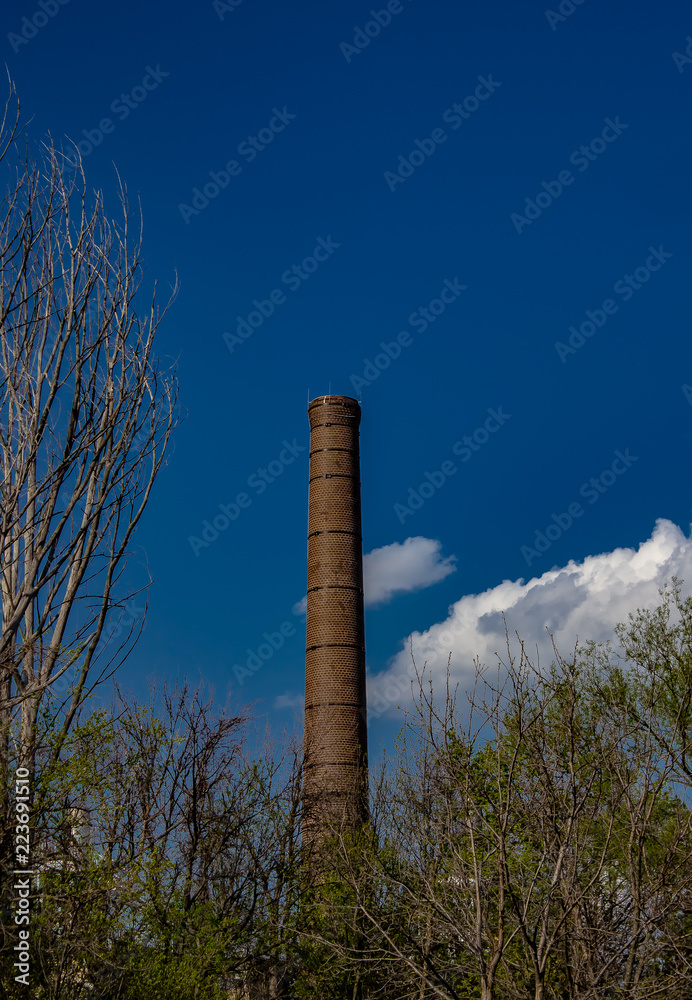 A retired smokestack in the distance against a blue sky with white clouds.