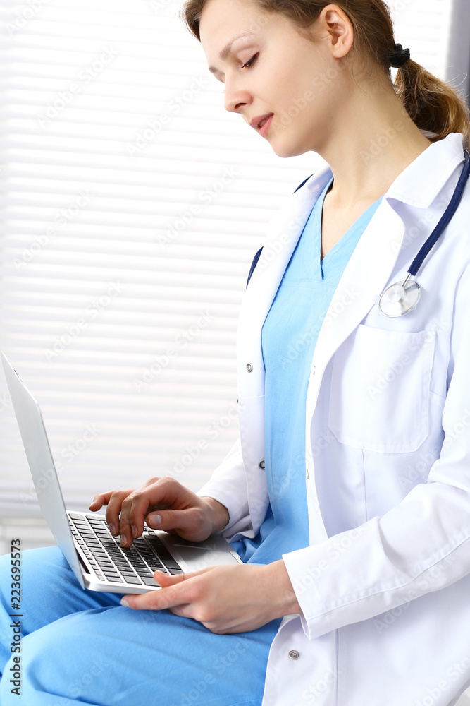 Woman doctor typing on laptop computer while working in hospital office. Data in medicine and health care Woman doctor typing on laptop computer while working in hospital office. Data in medicine and health care