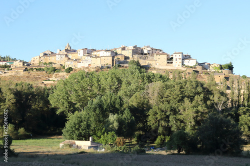 A landscape at sunset of Frago, a traditional Aragonese town over a hill surrounded by cultivated fields, firs and the typical Mediterranean forest in Spain