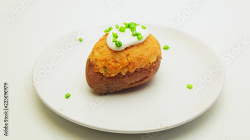 Stuffed Potatoes decorated with Spring Onion on a White Plate on a White Background.