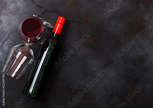 Elegant glass and bottle of red wine on stone kitchen table background. Top view. Space for text