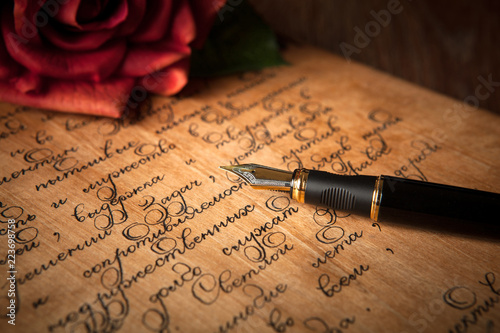 fountain pen on letter with text and red rose on a table