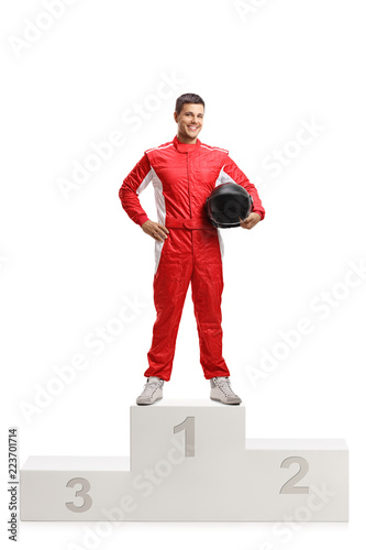 Male racer winner on a winner's pedestal holding a helmet