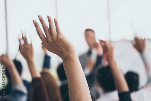 Audience raising hands up while businessman is speaking in training at the office. photo