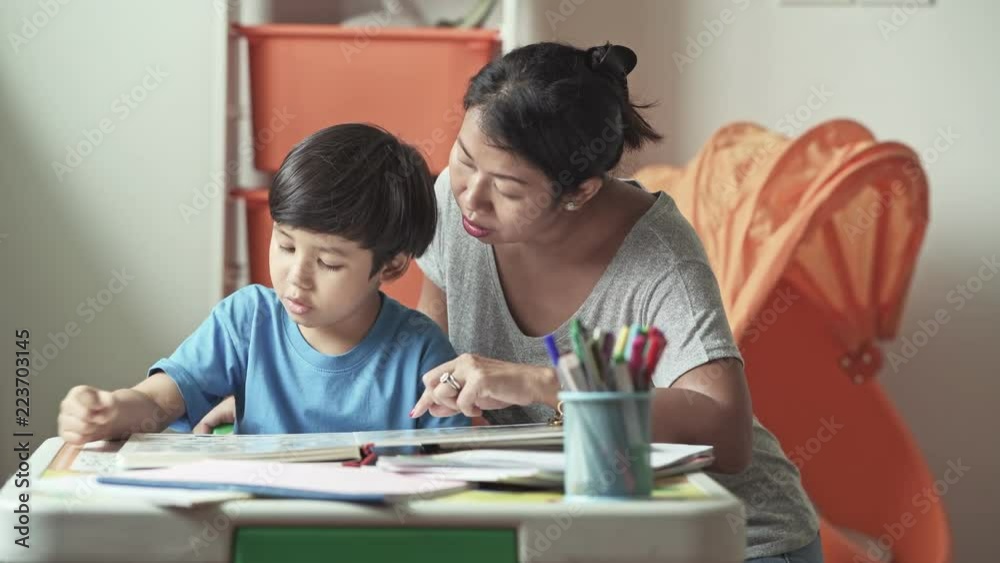 Children homework. Young mixed race boy doing homework in terrace at home. Reading book with his mother. Happy mood. Back to school concept. Children homework. Young mixed race boy doing homework in terrace at home. Reading book with his mother. Happy mood. Back to school concept.