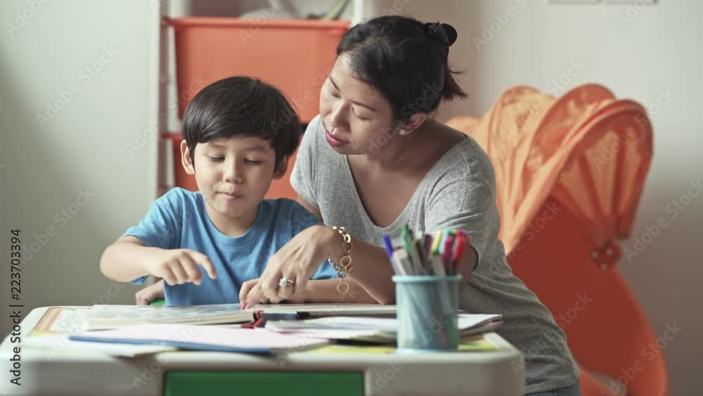 Children homework. Young mixed race boy doing homework in terrace at home. Reading book with his mother. Happy mood. Back to school concept. Children homework. Young mixed race boy doing homework in terrace at home. Reading book with his mother. Happy mood. Back to school concept.