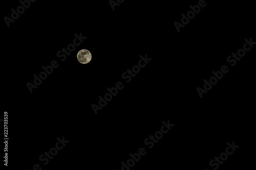 Real snapshot of the full moon in a low key on a black background