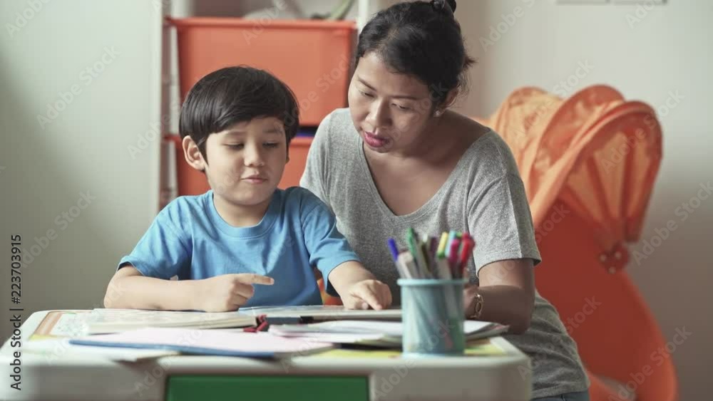 Children homework. Young mixed race boy doing homework in terrace at home. Reading book with his mother. Happy mood. Back to school concept. Children homework. Young mixed race boy doing homework in terrace at home. Reading book with his mother. Happy mood. Back to school concept.