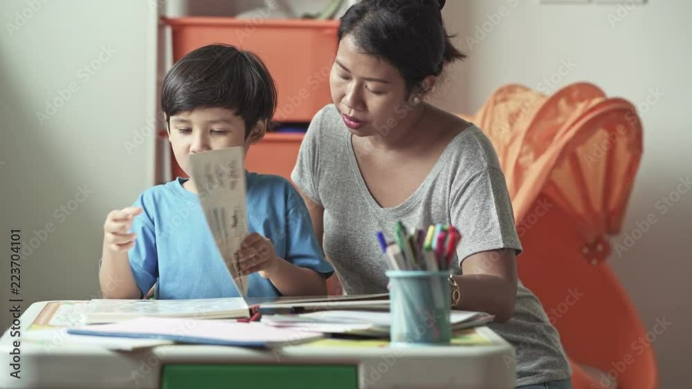 Children homework. Young mixed race boy doing homework in terrace at home. Reading book with his mother. Happy mood. Back to school concept. Children homework. Young mixed race boy doing homework in terrace at home. Reading book with his mother. Happy mood. Back to school concept.