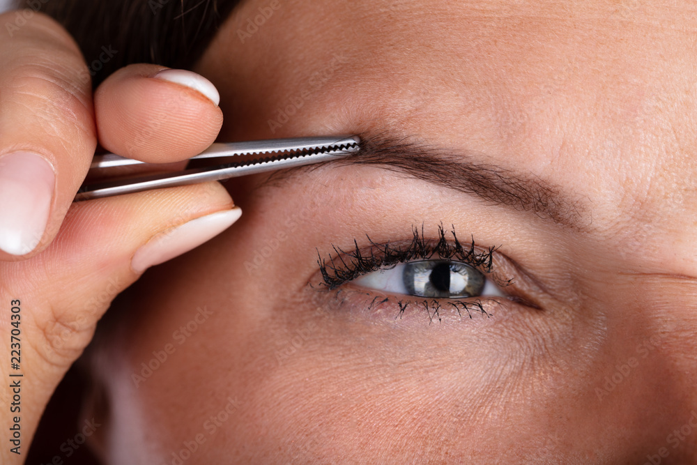 Woman Plucking Eyebrow Hair With Tweezers