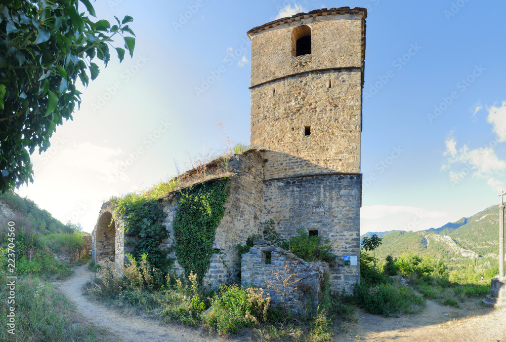 The Iglesia de San Miguel church and the bell tower covered with climbing ivy in Janovas, a ruined village in the Aragonese Pyrenees abandoned during the sixties due to the building of a dam