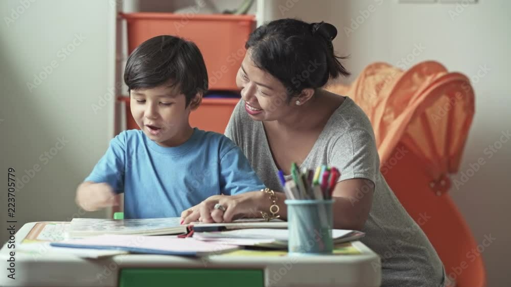 Children homework. Young mixed race boy doing homework in terrace at home. Reading book with his mother. Happy mood. Back to school concept. Children homework. Young mixed race boy doing homework in terrace at home. Reading book with his mother. Happy mood. Back to school concept.