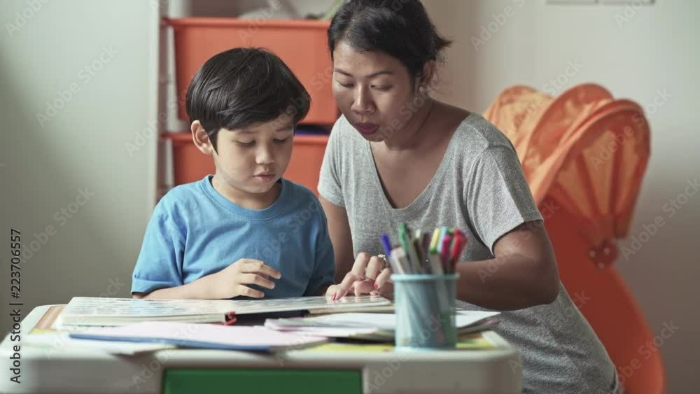 Children homework. Young mixed race boy doing homework in terrace at home. Reading book with his mother. Happy mood. Back to school concept. Children homework. Young mixed race boy doing homework in terrace at home. Reading book with his mother. Happy mood. Back to school concept.
