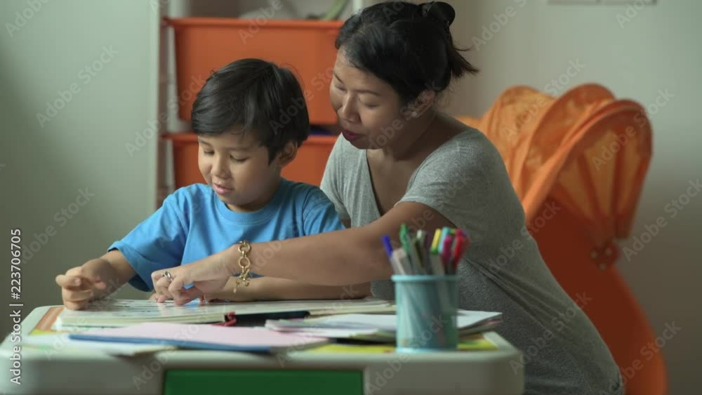 Children homework. Young mixed race boy doing homework in terrace at home. Reading book with his mother. Happy mood. Back to school concept. Children homework. Young mixed race boy doing homework in terrace at home. Reading book with his mother. Happy mood. Back to school concept.