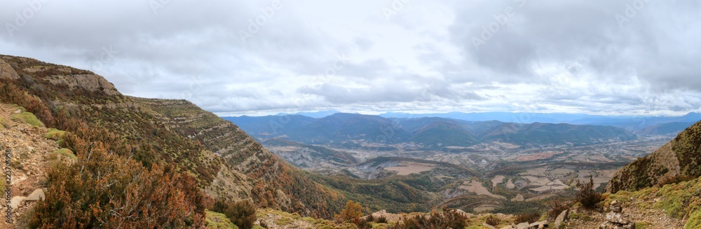 Blue cloudy sky and typical mountains and hills covered with forest met in autumn while hiking from the small Yebra de Basa town to Santa Orosia church on the Pyrenees mountains, Aragon, Spain