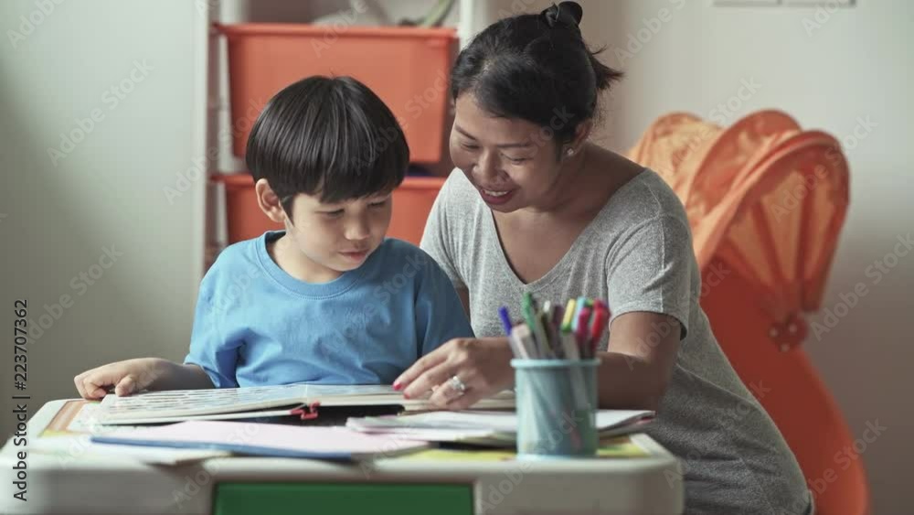 Children homework. Young mixed race boy doing homework in terrace at home. Reading book with his mother. Happy mood. Back to school concept. Children homework. Young mixed race boy doing homework in terrace at home. Reading book with his mother. Happy mood. Back to school concept.