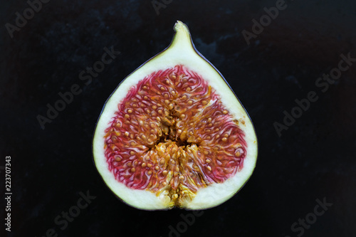 Fresh ripe fig cut in half over dark background, close up.