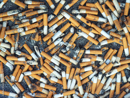 Ashtray, cigarette butts background. Lot of burnt cigarette and ash, close-up