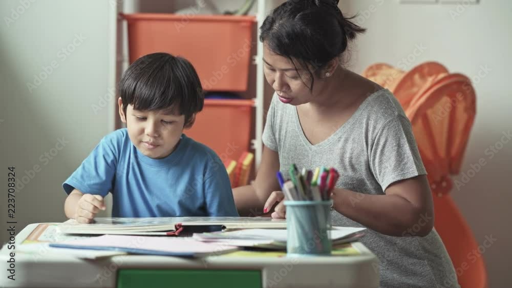 Children homework. Young mixed race boy doing homework in terrace at home. Reading book with his mother. Happy mood. Back to school concept. Children homework. Young mixed race boy doing homework in terrace at home. Reading book with his mother. Happy mood. Back to school concept.