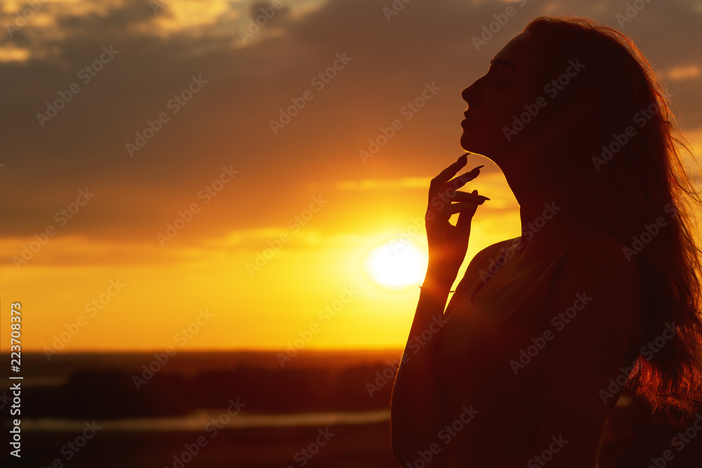 silhouette of a beautiful girl at sunset in a field, face profile of young  woman on nature Stock Photo