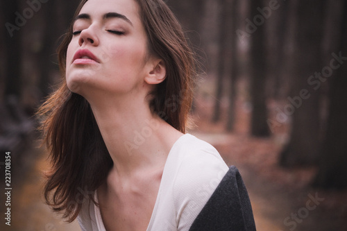 Attractive, charming young woman with long beautiful neck in white cotton dress and dark coat in autumn Park.