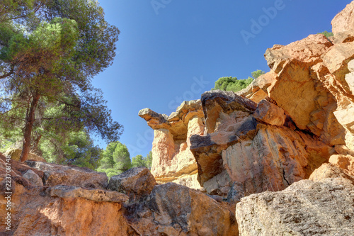 A protruding red rock with trees and a deep blue sky in the canyon style hills of Anento, a small town in Aragon, Spain