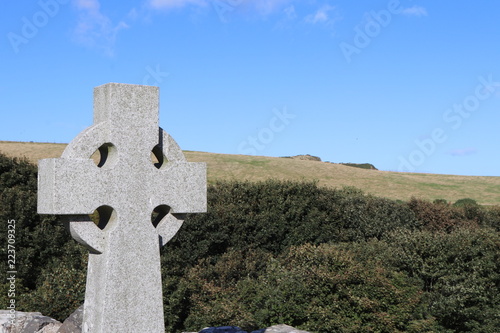 Stone celitc cross in close up against grass and glue sky photo