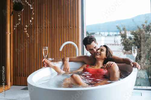 Stampa su tela Couple enjoying a bath with champagne