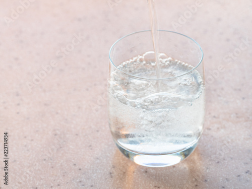 trickle of sparkling mineral water pours in glass